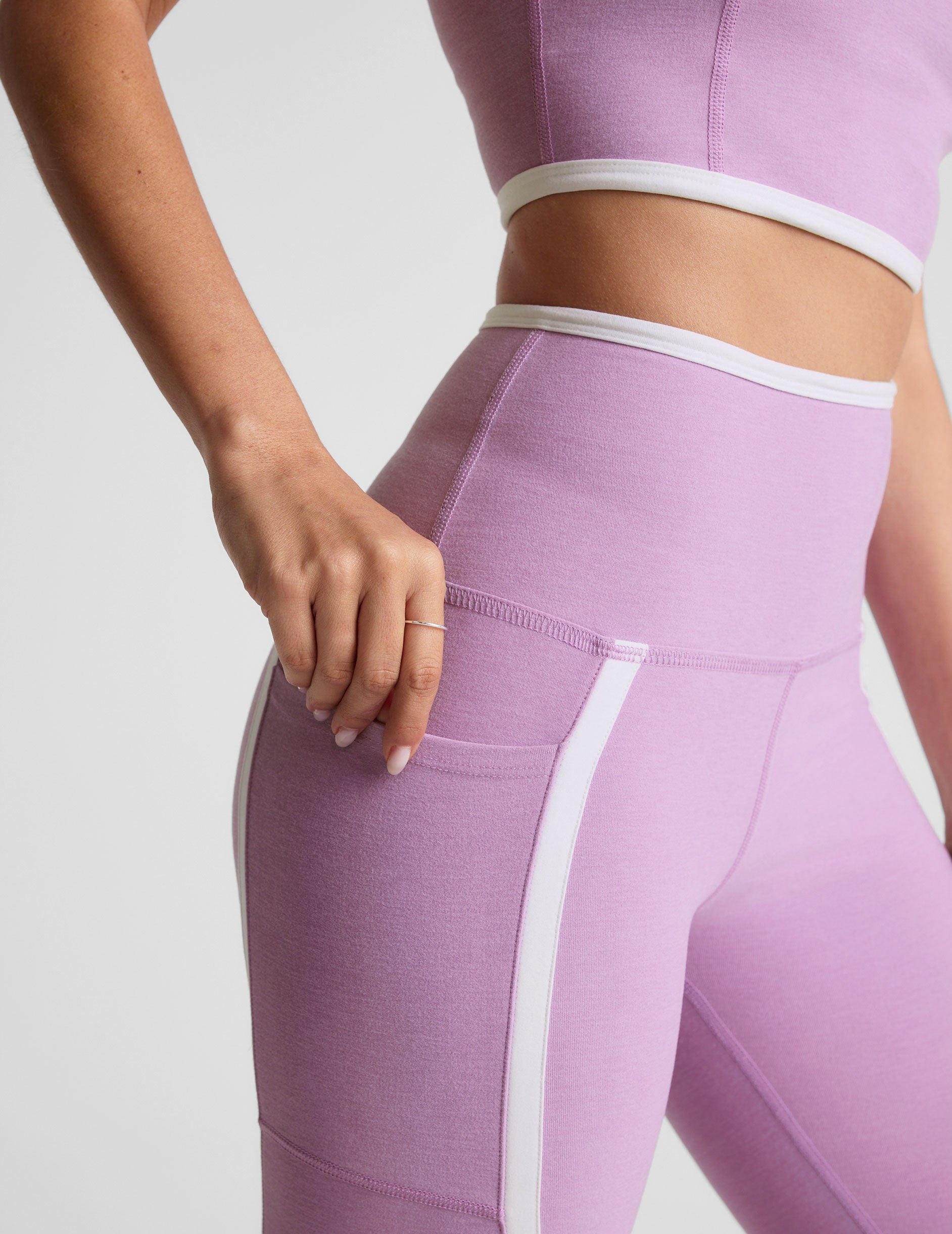 purple high-waisted midi length legging with pockets and white piping. 