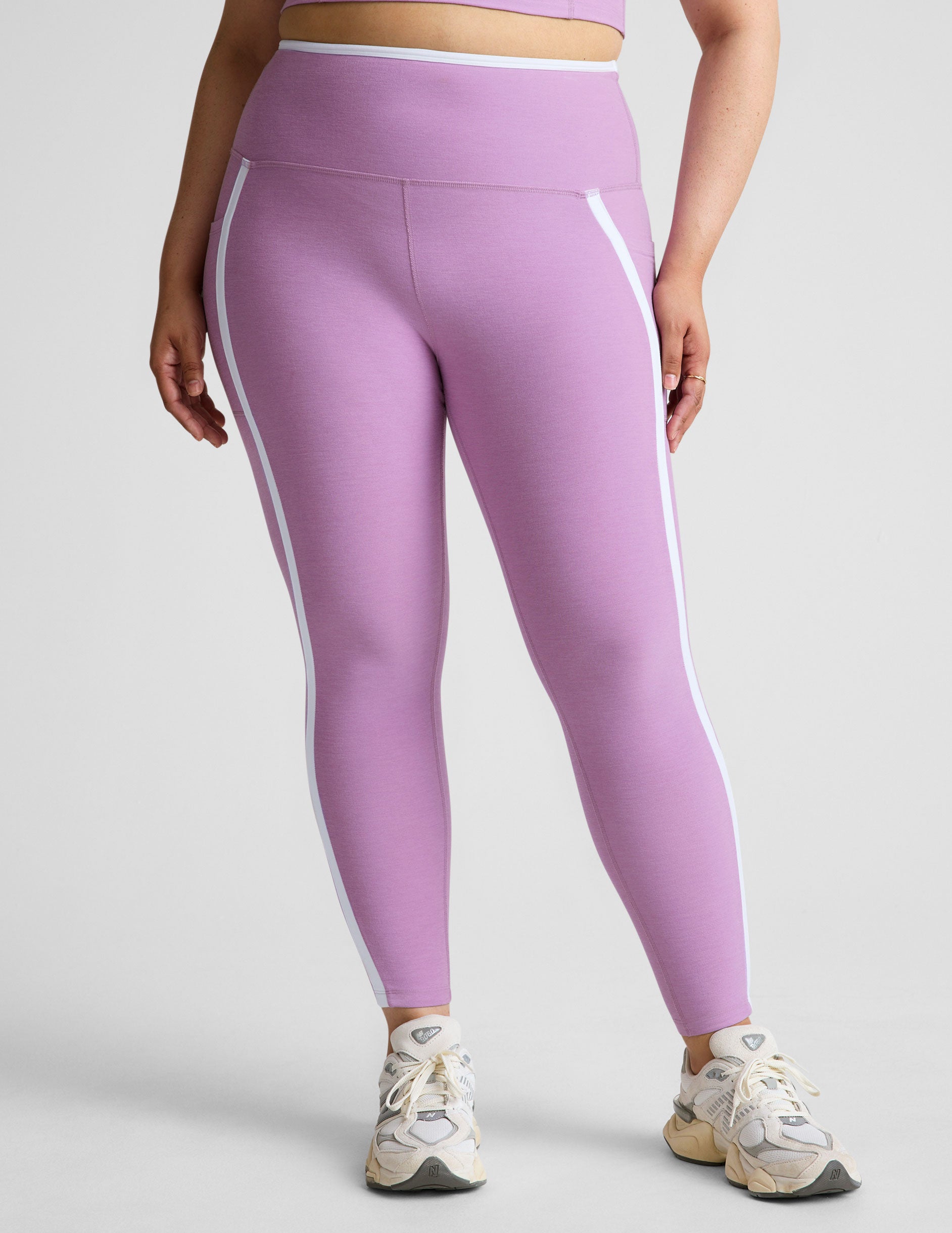 purple high-waisted midi length legging with pockets and white piping. 