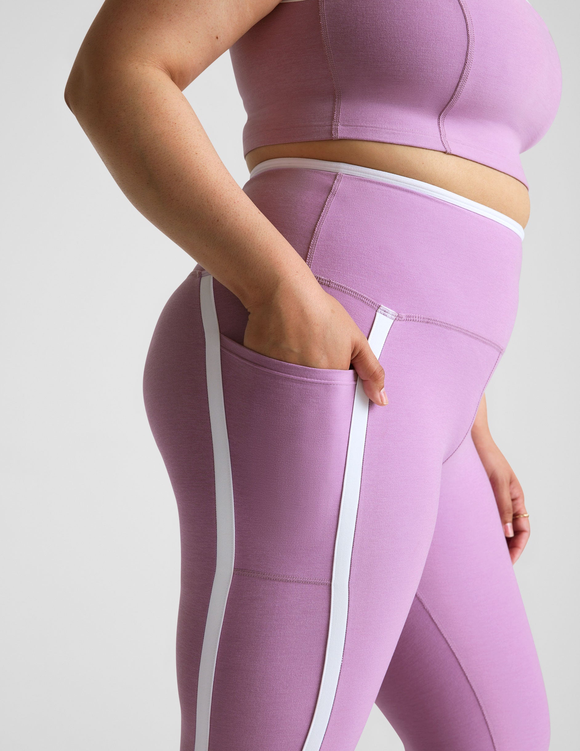 purple high-waisted midi length legging with pockets and white piping. 