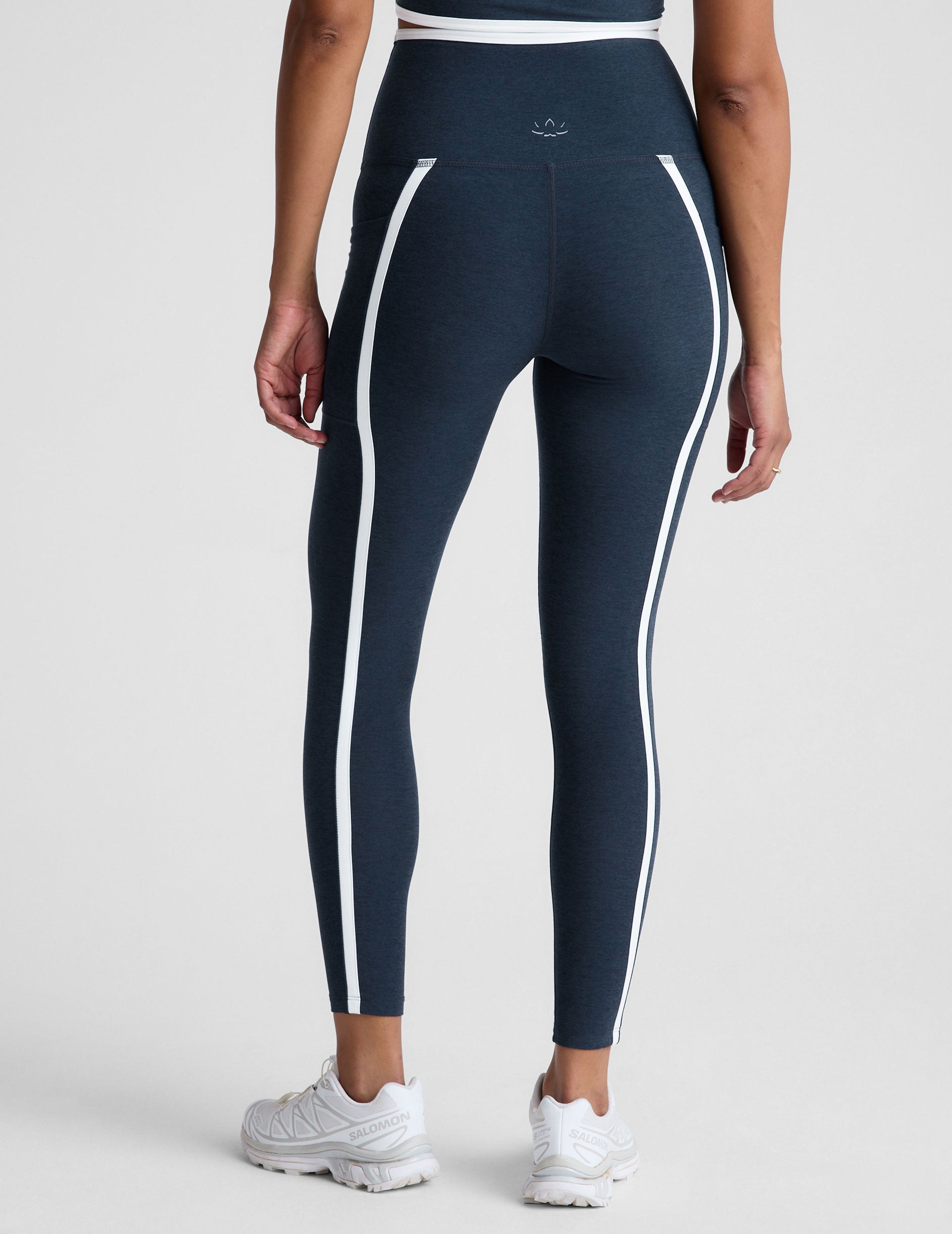 blue high-waisted midi length leggings with pockets and white piping. 