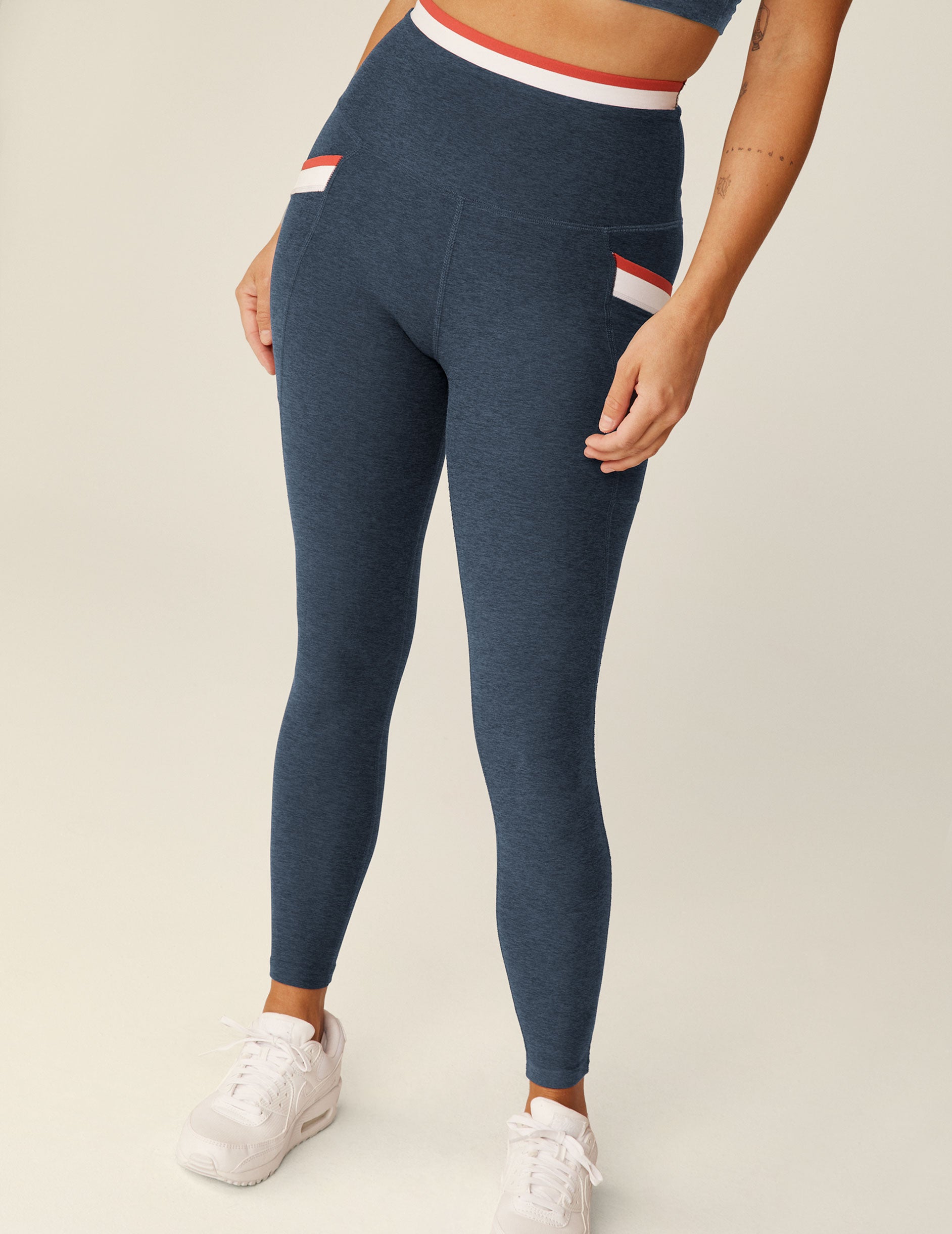 blue high-waisted midi legging with white and red outlining along the waistband and pockets. 