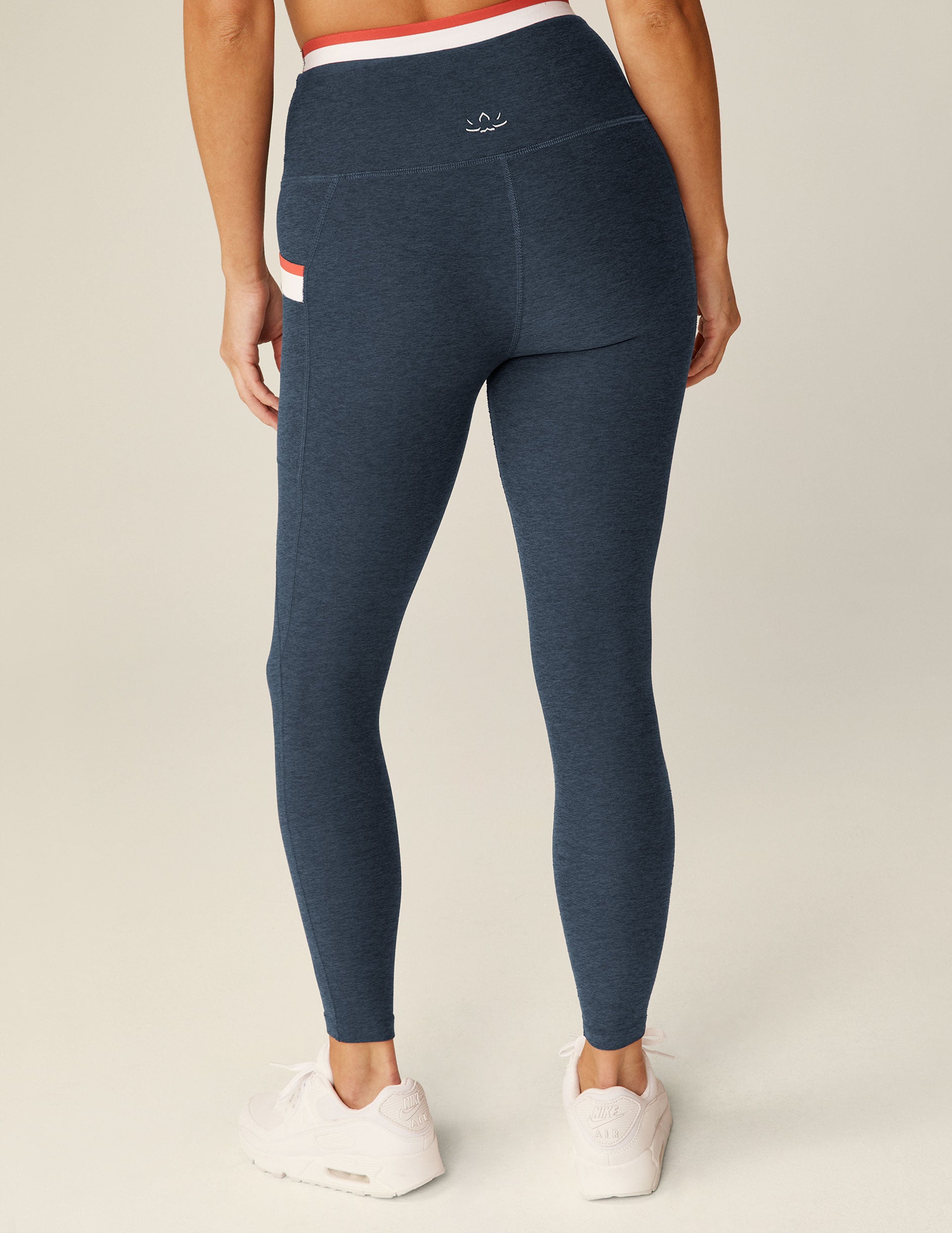 blue high-waisted midi legging with white and red outlining along the waistband and pockets. 