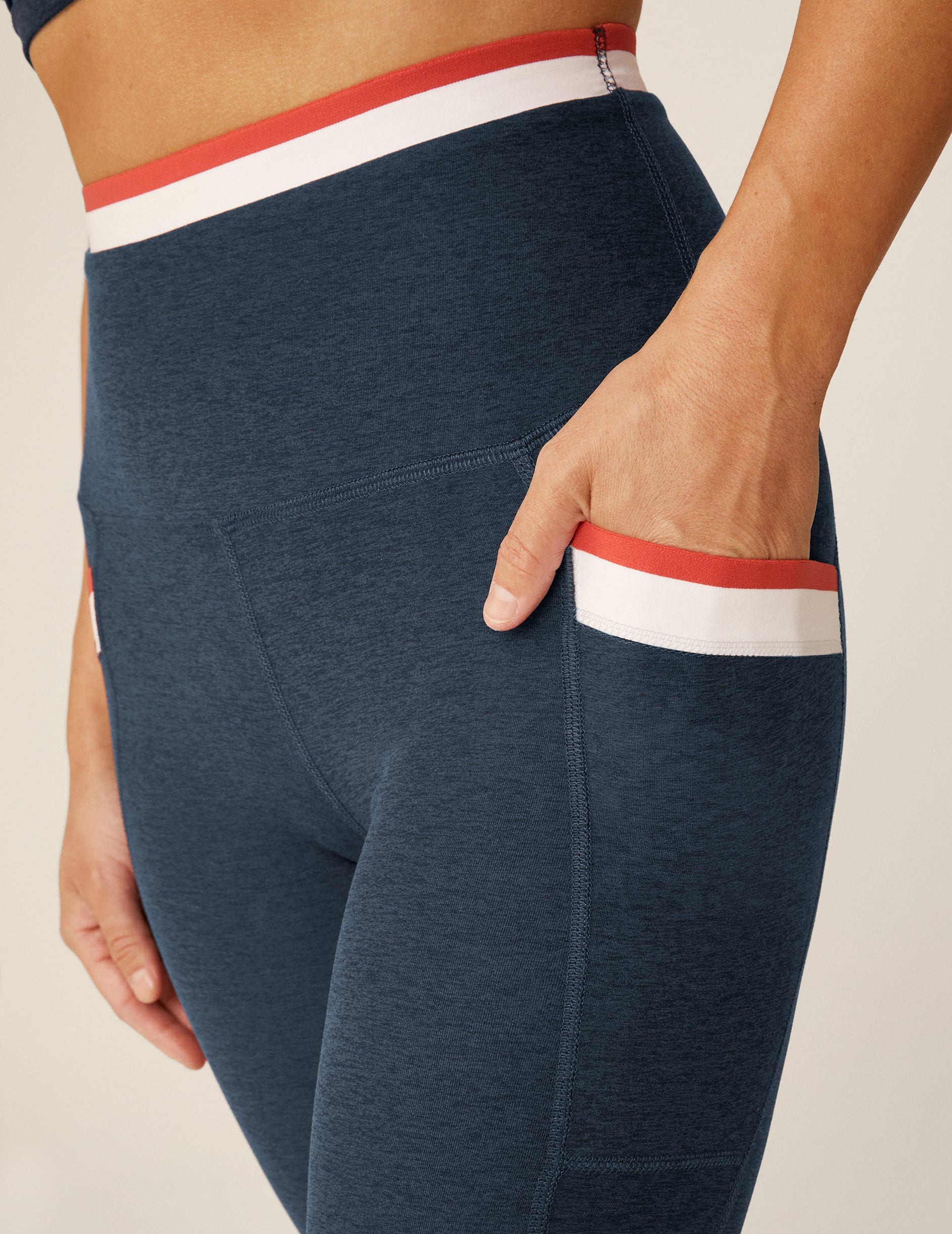 blue high-waisted midi legging with white and red outlining along the waistband and pockets. 