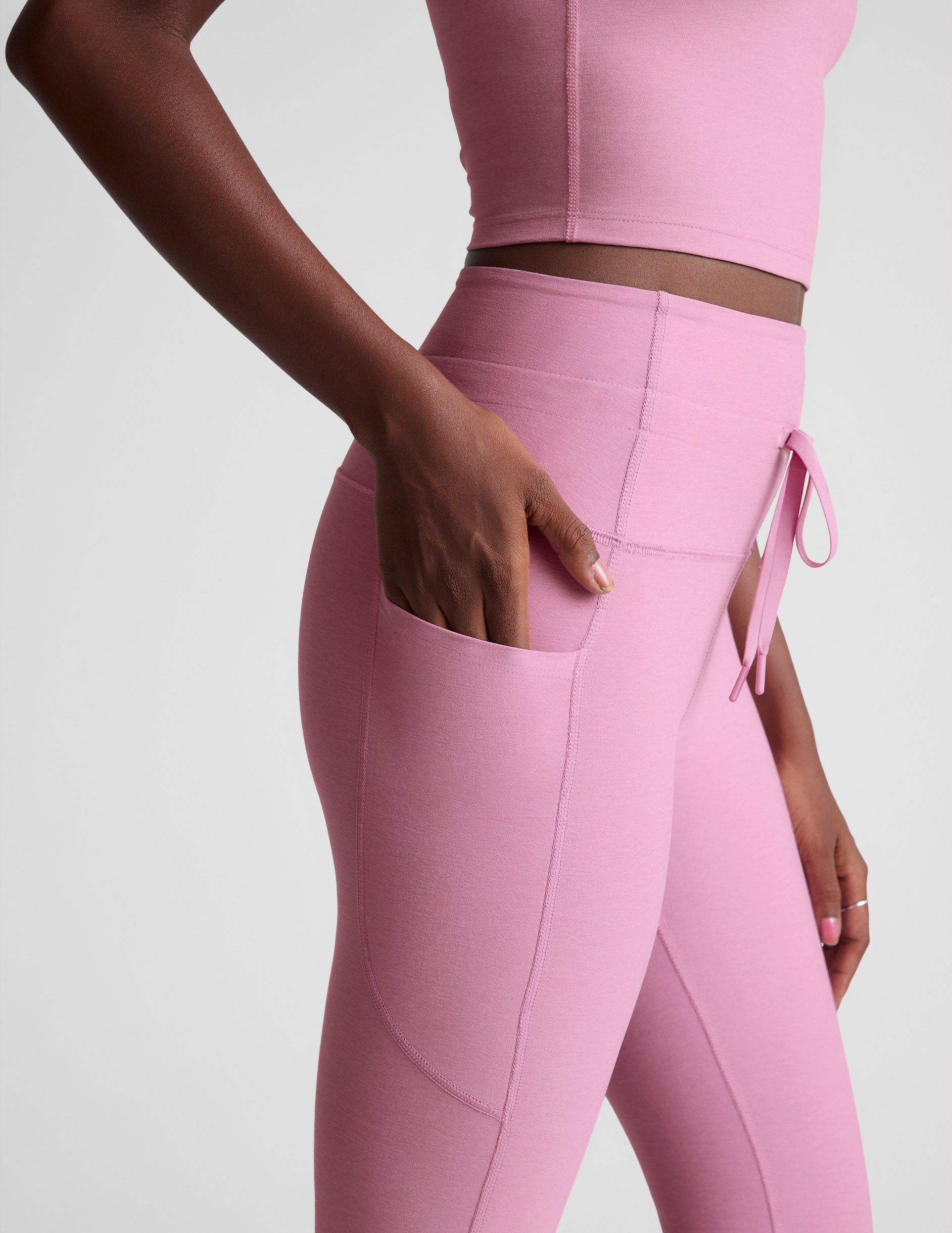 pink high-waisted midi length leggings with a drawstring at the waist and side pockets. 