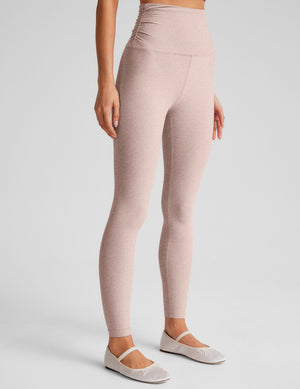 model wearing a pink cropped tank top and pink high-waisted midi length leggings on a plain background. 
