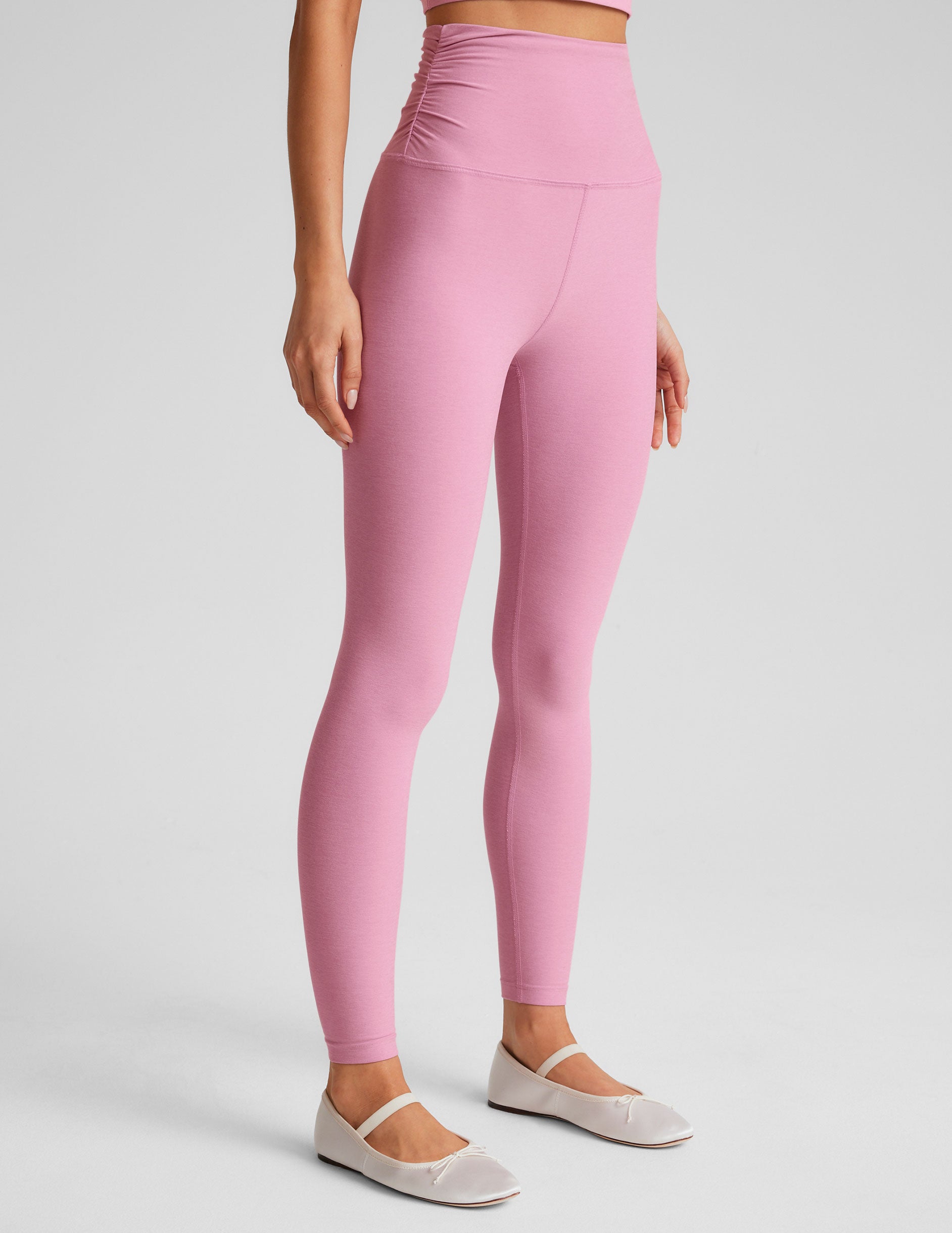 pink high-waisted midi length leggings with shirred detailing on the side of each waistband. 