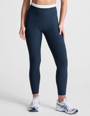 navy blue high-waisted midi leggings with white contrast piping on side of leg and around waistband. 