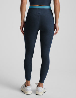 Woman wearing a navy sports bra and leggings set on a light gray background. 