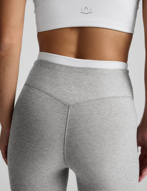 Person wearing a white crop top and gray leggings on a light gray background.