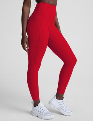 woman wearing red high-waisted pocket leggings on a plain background. 