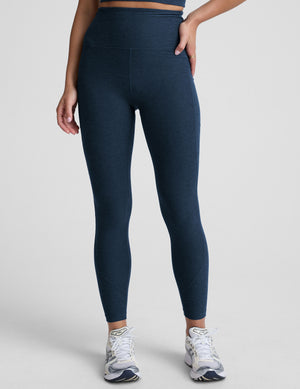 model wearing blue midi length leggings with 3 pockets against a plain background. 