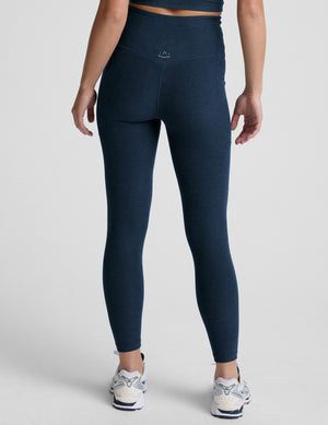 model wearing blue midi length leggings with 3 pockets against a plain background. 