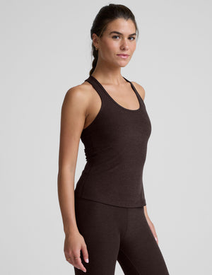 woman wearing a brown racerback and full length tank top and leggings on a plain background. 