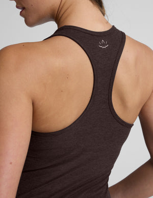 woman wearing a brown racerback and full length tank top and leggings on a plain background. 