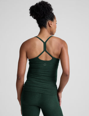 pregnant model wearing green maternity racerback tank top and green maternity leggings on a plain background. 