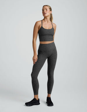 woman wearing a charcoal gray racerback cropped tank and leggings on a plain background. 