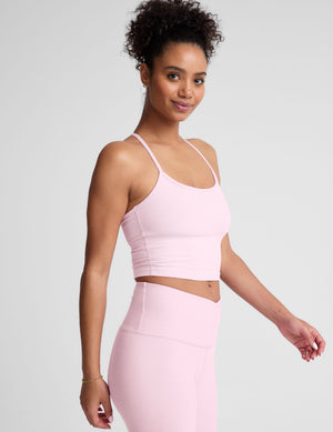 Woman wearing a pink sports bra and leggings on a light gray background