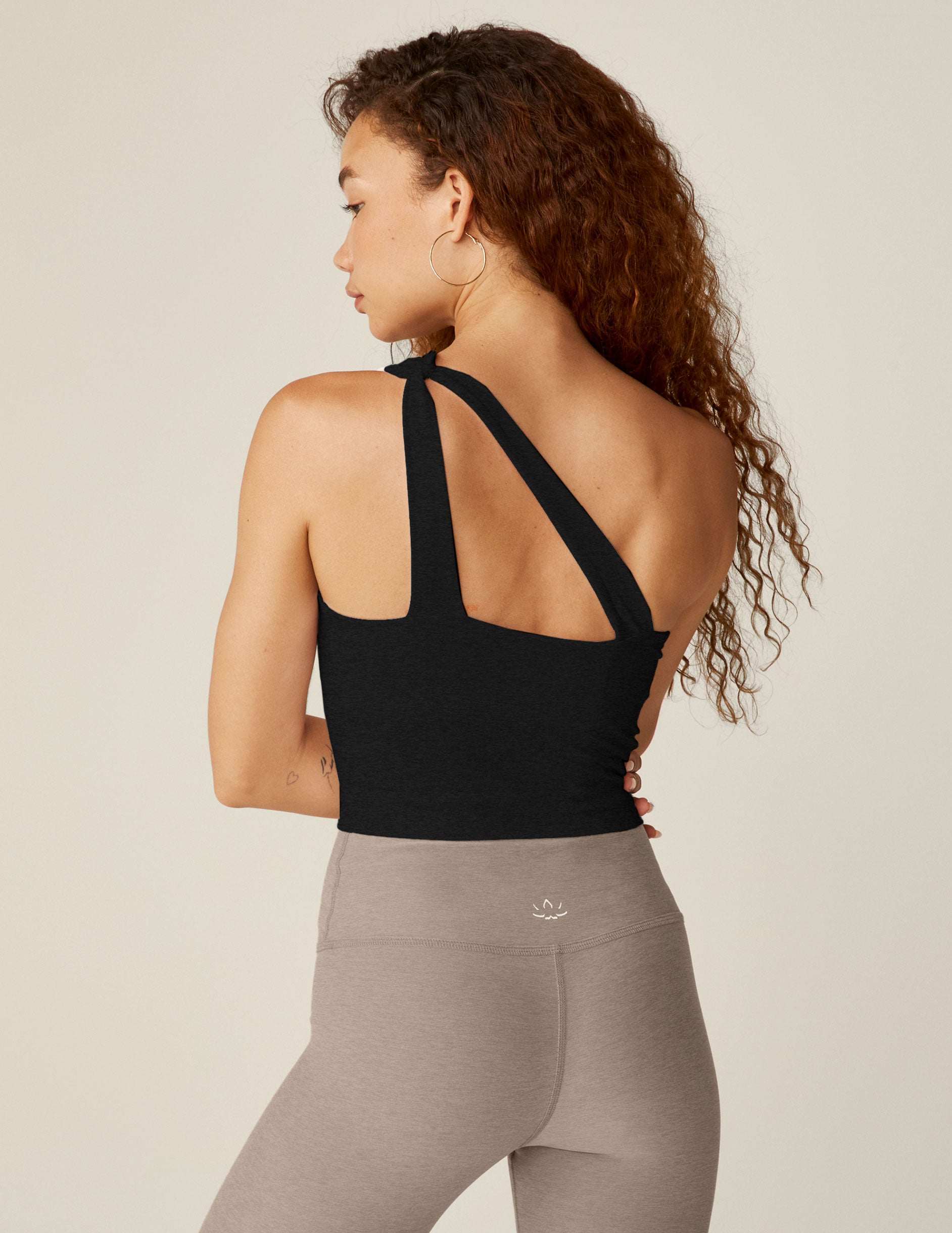black one-shoulder cropped tank with a cutout on the front strap and a detailing on the back strap. 