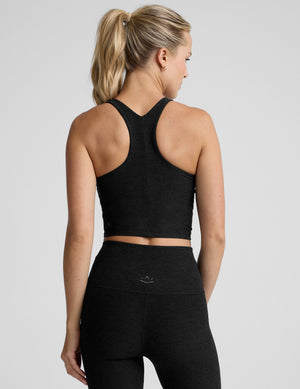 woman wearing a black high neck racerback cropped tank on a plain background. 