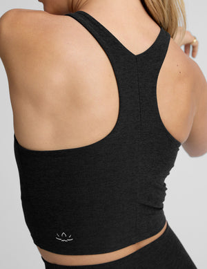 woman wearing a black high neck racerback cropped tank on a plain background. 