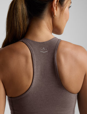 Woman wearing a brown v-neck racerback cropped tank and leggings on a light gray background. 