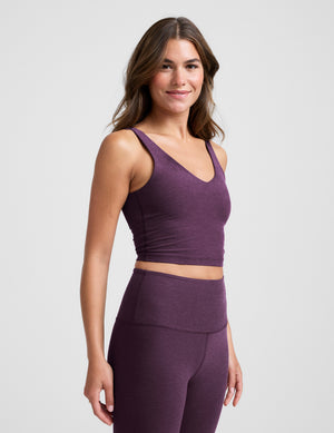 Woman wearing a purple athletic outfit on a light gray background. 