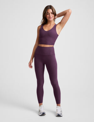 Woman wearing a purple athletic outfit on a plain background. 