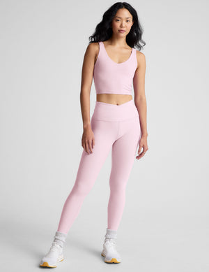 Woman wearing a pink athletic outfit with a plain background