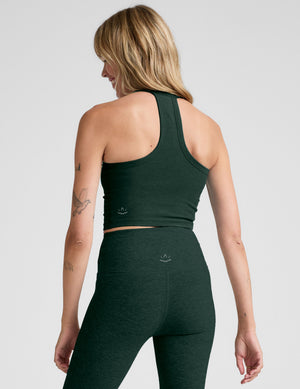 woman wearing a green v-neck racerback cropped tank and leggings on a light gray background. 