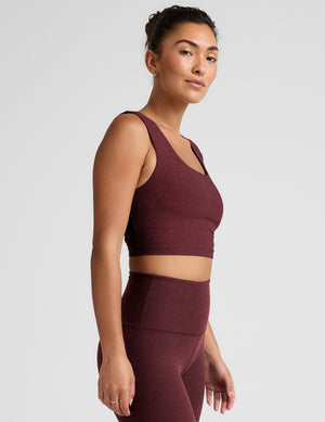 model is wearing a cropped square neck tank with thick straps. 