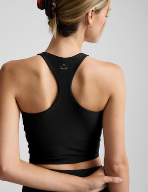 Woman wearing a black high-neck racerback cropped tank against a plain background. 