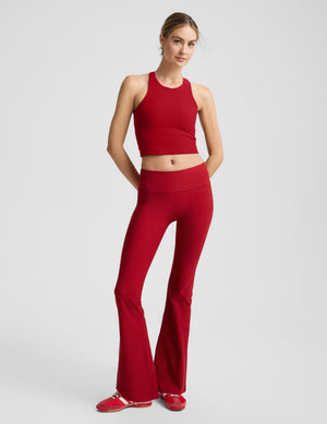 Woman wearing a red high neck racerback cropped tank on a light gray background. 