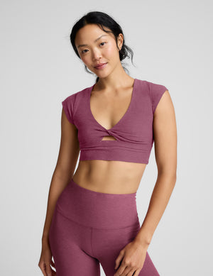 Woman wearing a mauve athletic outfit on a light gray background. 