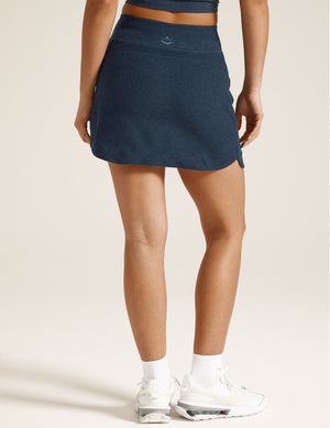 Woman wearing Navy Spacedye Movement Skirt™ with white sneakers, Rear view showing curved hem and wide waistband.