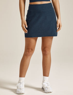Woman wearing Navy marled Spacedye Movement Skirt™ paired with white sneakers and socks. Front view.