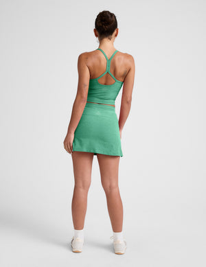Rear view of a woman wearing the green Spacedye Go Pocket Skirt, a high-waisted A-line mini skirt.