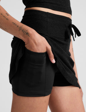 black mini active skirt with a drawstring at waistband and built in shorts with pockets. 