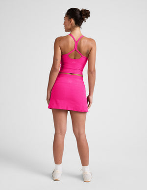 Rear view of a woman in the fuchsia Spacedye Go Pocket Skirt, a high-waisted mini A-line skirt in a bright jewel tone.