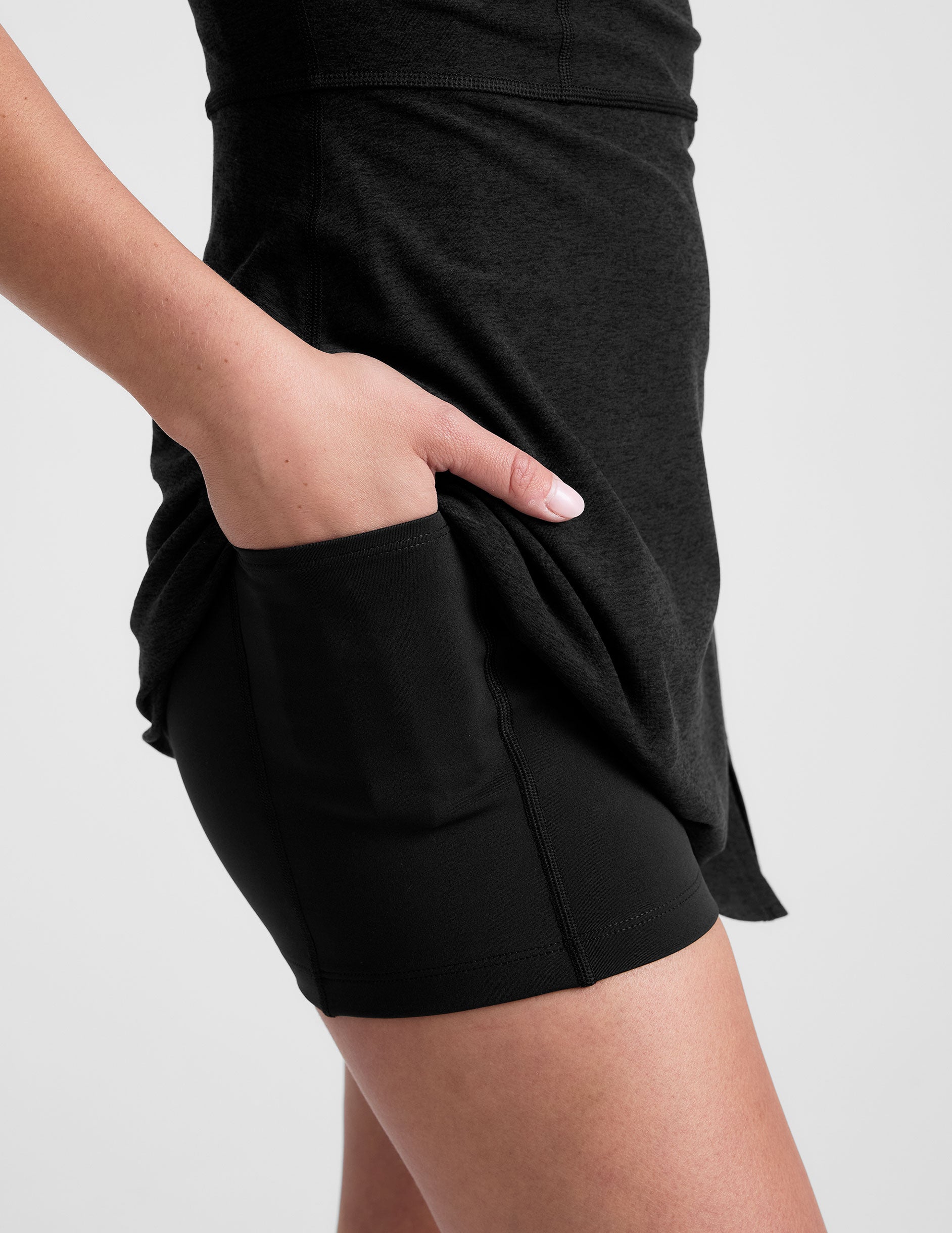 close-up image of a black mini active dress with a zipper on the front neckline and a side slit. 