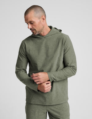 Man wearing a green hoodie and shorts set on a white background. 