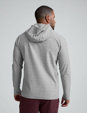 man wearing a gray hoodie and maroon shorts on a light gray background. 