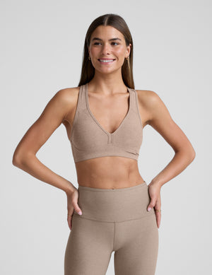 Woman wearing a beige bra with matching leggings against a plain background. 