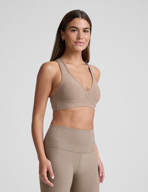 Woman wearing a beige bra with matching leggings against a plain background. 