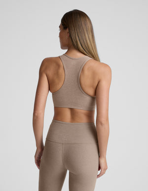 Woman wearing a beige bra with matching leggings against a plain background. 