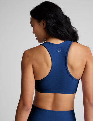 woman wearing a blue sports bra and leggings on a gray background. 