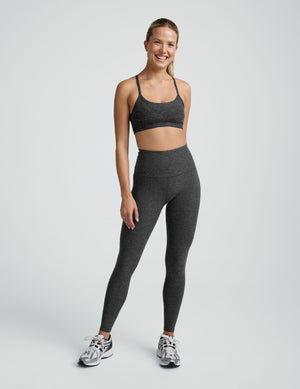 person wearing a black-charcoal slim racerback bra with matching leggings against a plain background. 