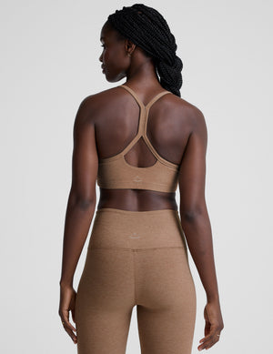 model wearing a brown slim strapped racerback bra and leggings on a light gray background. 