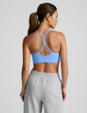 Woman wearing a blue racerback bra and gray sweatpants on a plain background. 
