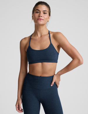 person wearing a blue slim racerback bra with leggings against a plain background. 