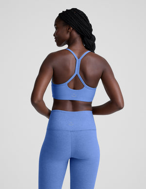 Woman wearing a blue sports bra and leggings on a light gray background. 